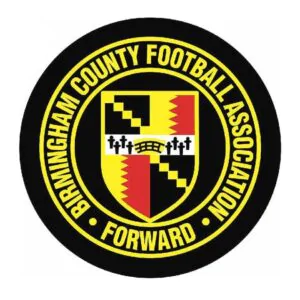 Circular logo for Birmingham County Football Association featuring a shield with black, red, and yellow sections, surrounded by the words "Birmingham County Football Association Forward.